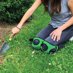 Frau bei Gartenarbeit mit gepolsterten Knieschonern auf der Wiese kniend.