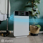 Der Livington Air Purifier steht im modernen Raum neben einer Pflanze und reinigt die Luft.