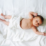 Baby liegt auf weißer Decke