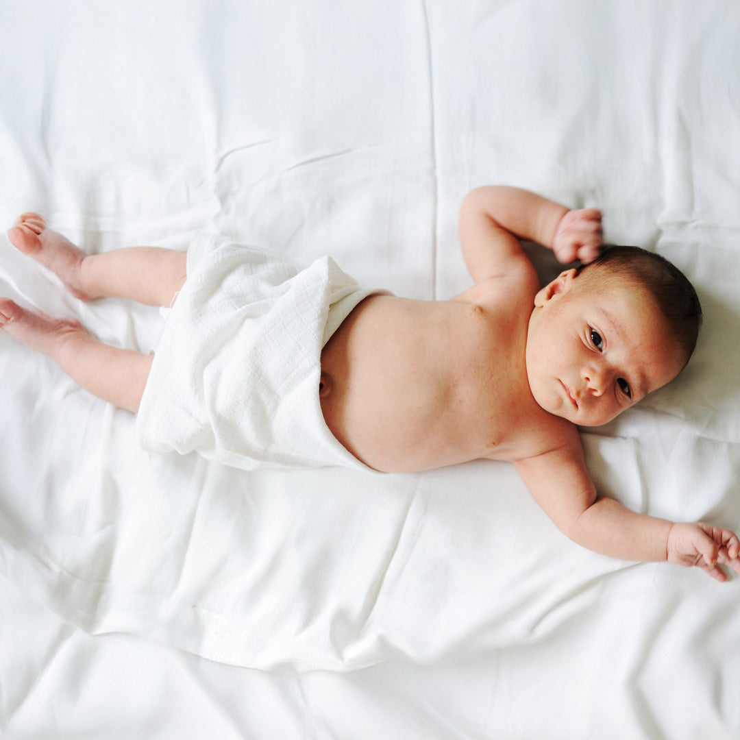 Baby liegt auf weißer Decke