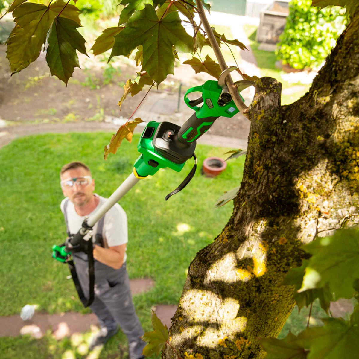 Mann schneidet mit der Hammersmith Akku-Gartenschere kombiniert mit dem Teleskopstiel einen Ast