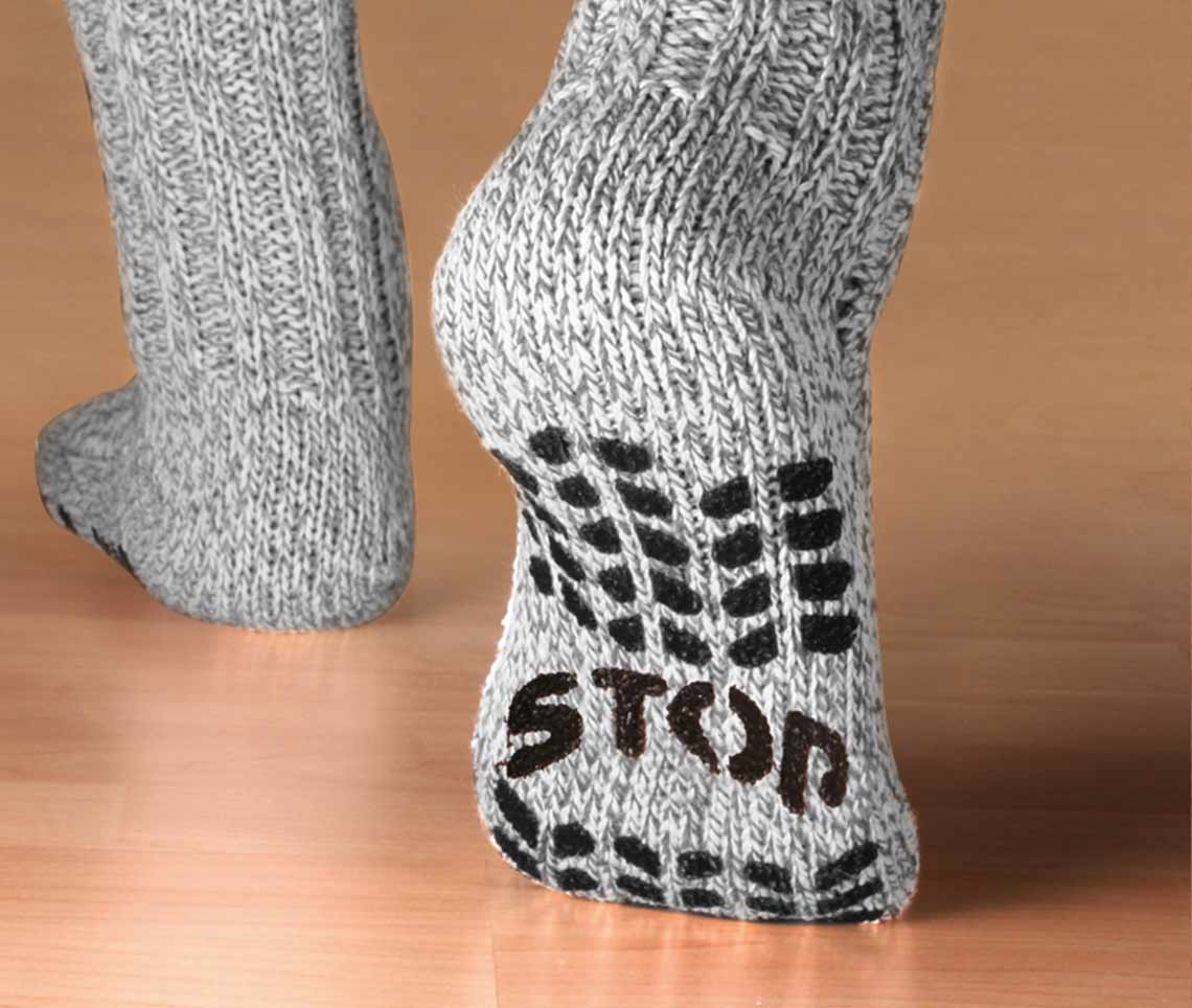 Graue Stricksocken mit rutschfestem ABS-Aufdruck „STOP“ auf der Sohle.