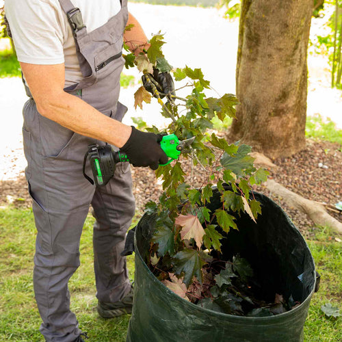 Mann zerkleinert Äste mit der Hammersmith Akku-Gartenschere und füllt sie in Gartensack