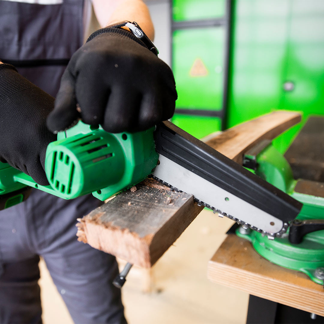 Mini-Kettensäge mit Elektroantrieb beim Schneiden eines Holzstücks