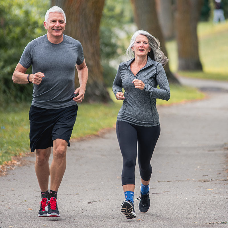 Neuro Socks Athletic – aktives Paar beim Joggen im Park, trägt funktionelle Sportsocken.