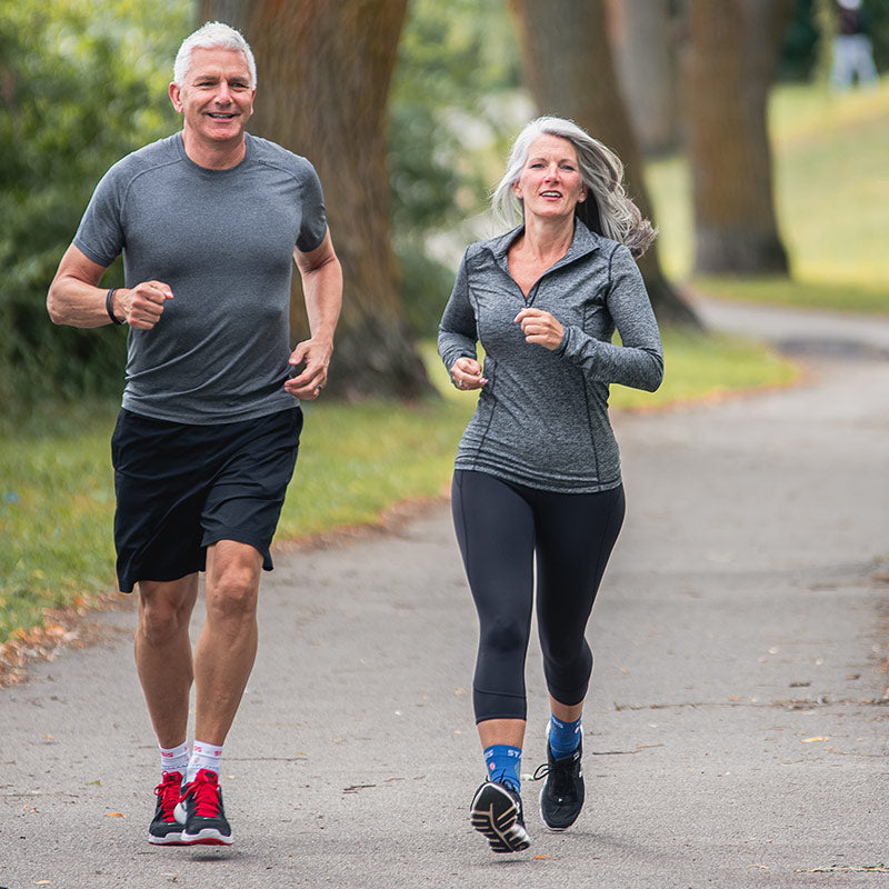 Neuro Socks Athletic – sportliches Paar joggt im Park und trägt Sportsocken.