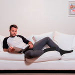 Neuro Socks Wellness – Mann liest entspannt auf dem Sofa, trägt schwarze Wellness-Socken.