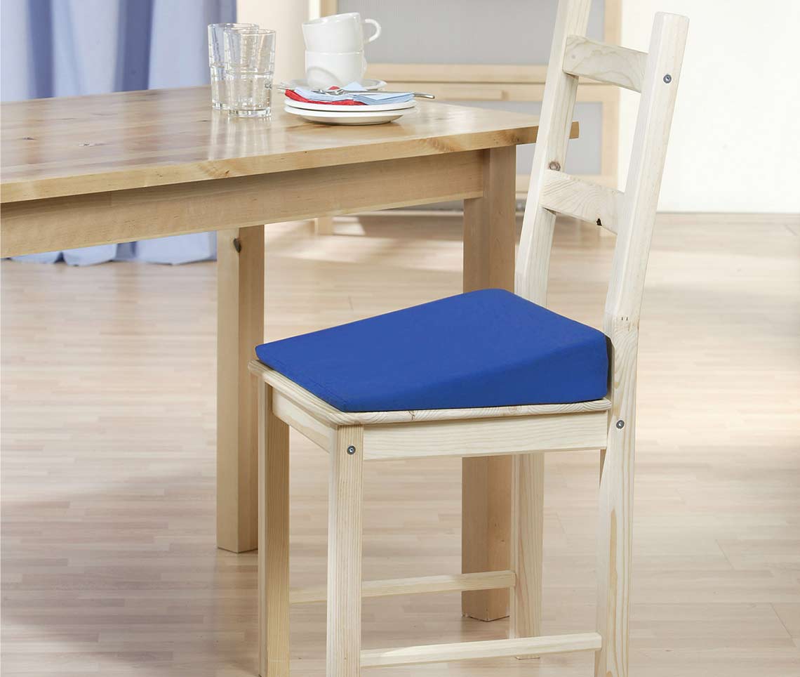 Keilkissen auf einem Holzstuhl zur ergonomischen Unterstützung beim Sitzen.