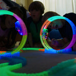 Kinder beobachten leuchtende Fantastic-Tracks-Loopings und ihre Autos im Dunkeln.