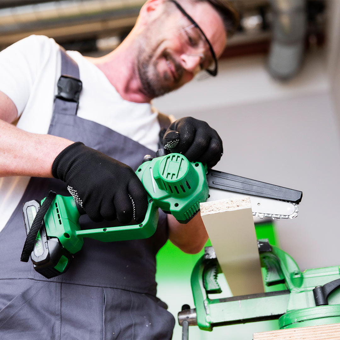 Heimwerker sägt Holz mit grüner Mini-Kettensäge