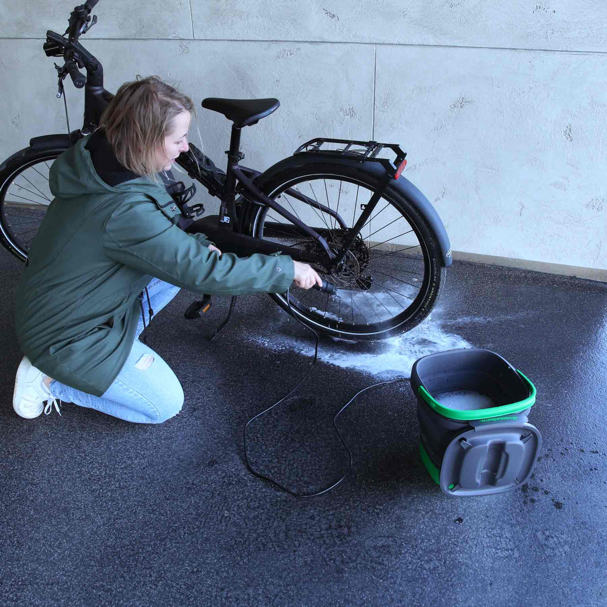 Frau reinigt mit dem Hammersmith Pressure Bucket das Hinterrad eines Fahrrads