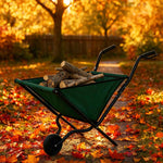 Hammersmith faltbare Schubkarre, gefüllt mit Holz, steht auf einem herbstlich mit buntem Laub bedeckten Gartenweg