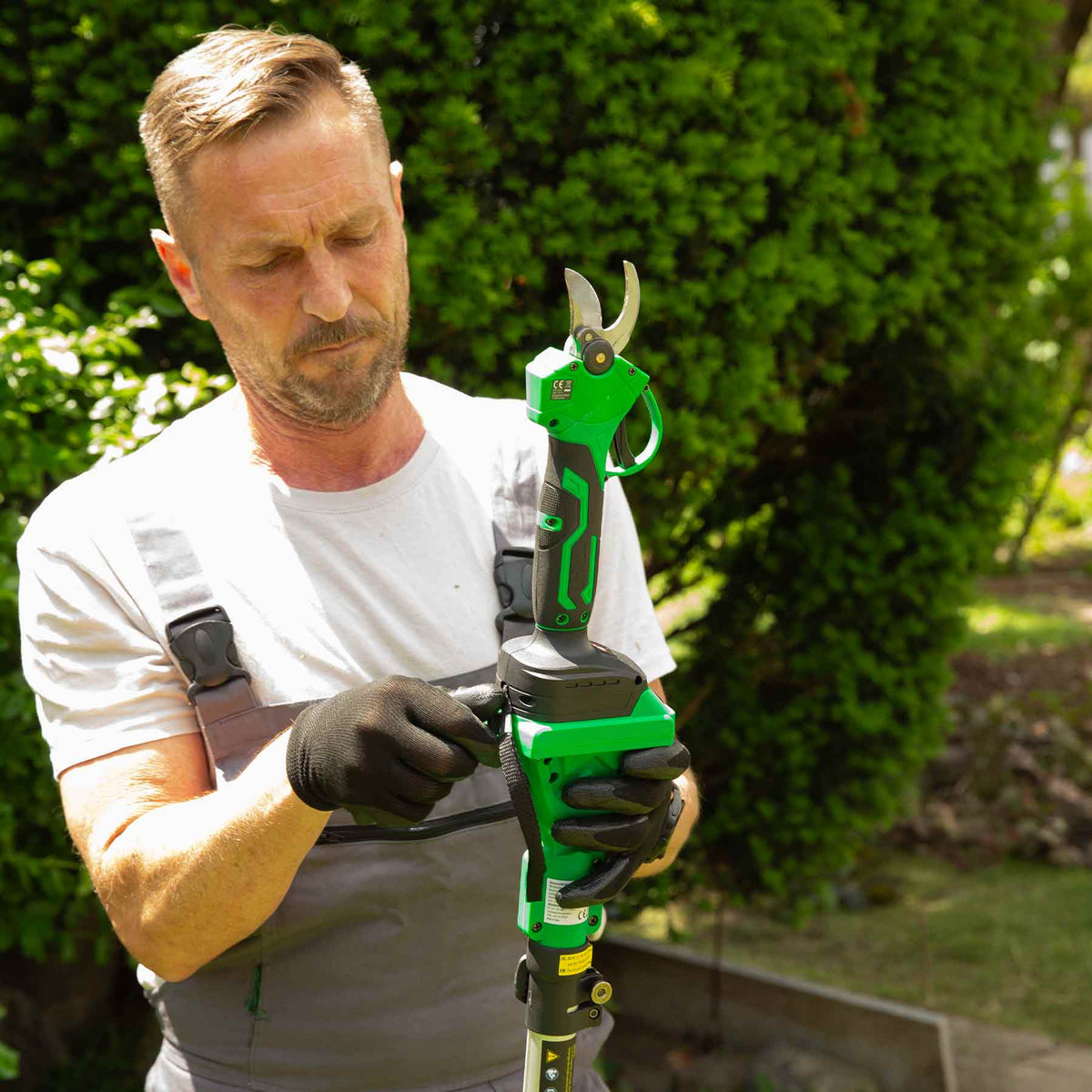 Mann befestigt die Hammersmith Akku-Gartenschere auf den Teleskopstiel