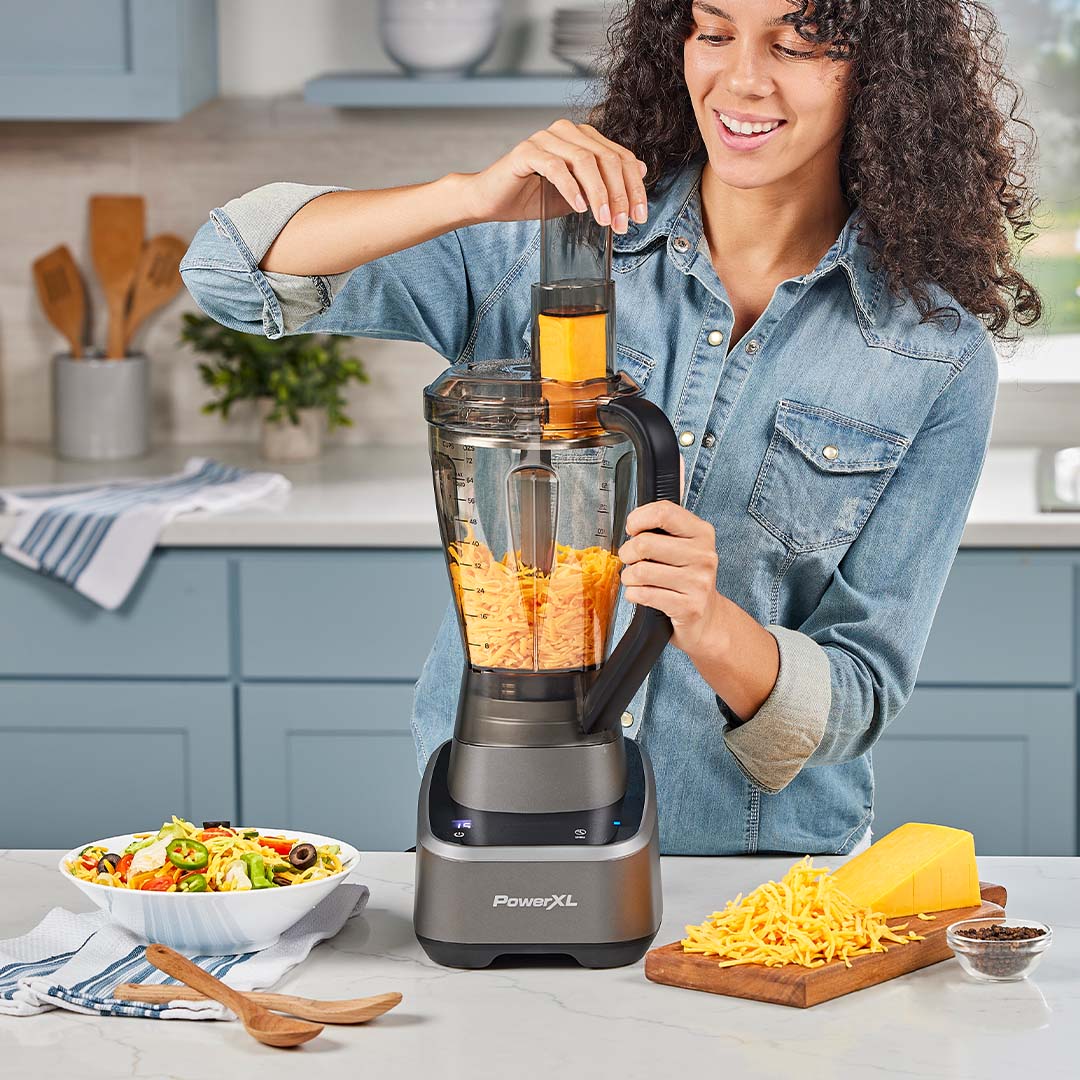 Frau nutzt den PowerXL SenseMax Küchenmixer, um Käse zu zerkleinern