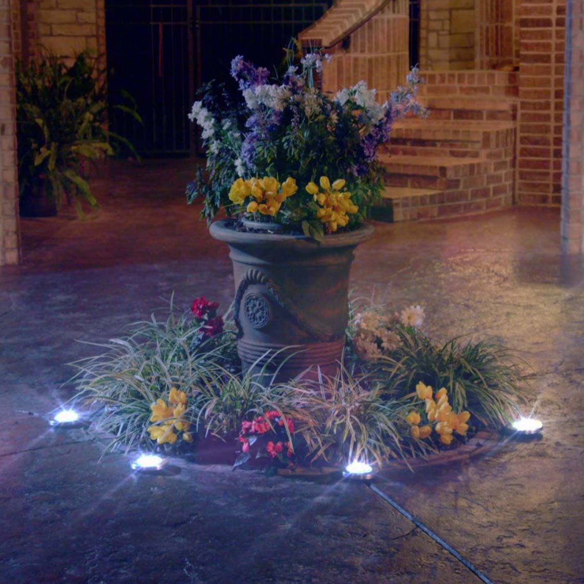 Blumentopf im Hof von LED-Solarleuchten umrandet.