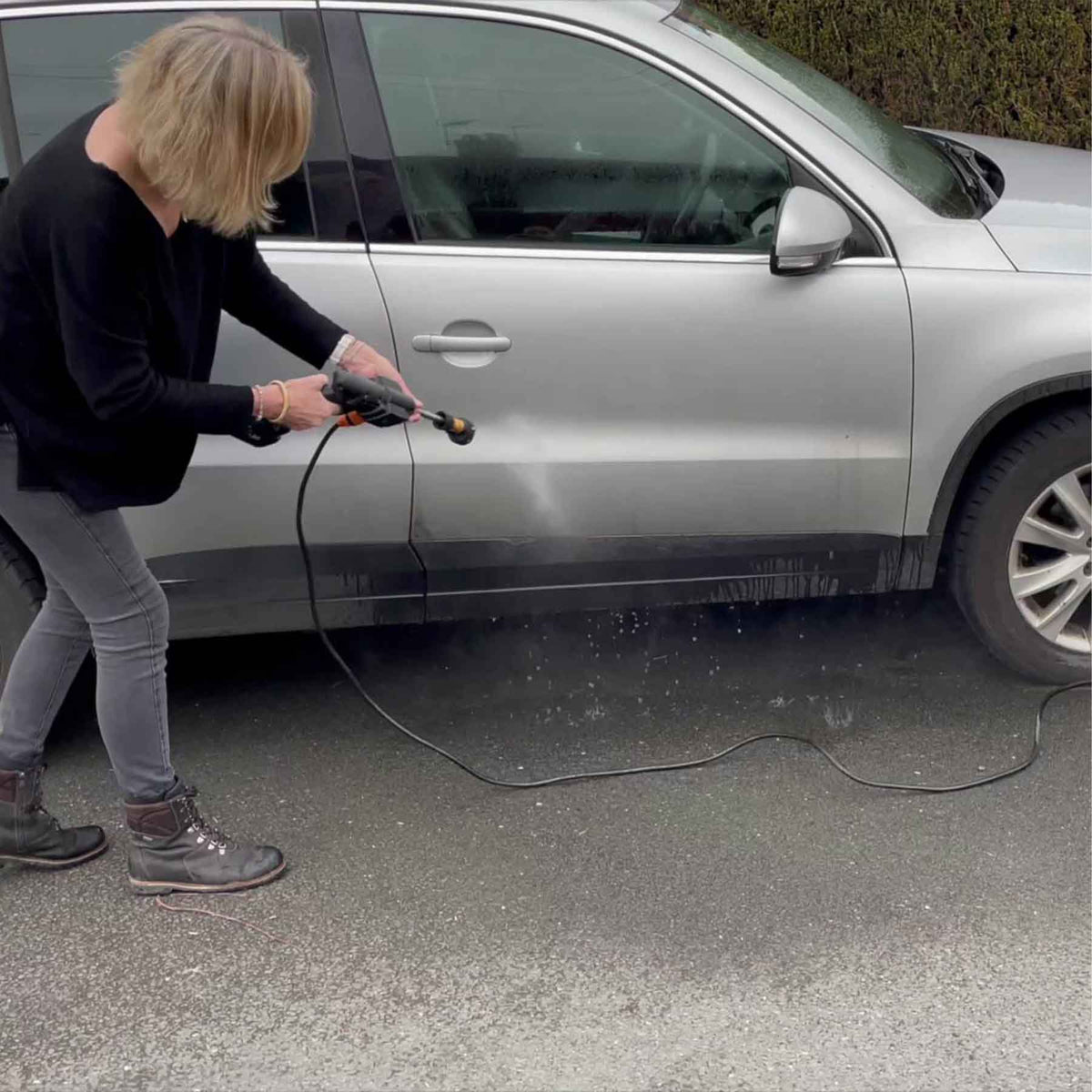 Eine Frau reinigt ein Auto mit dem Hochdruckreiniger Hammersmith JetHawk.