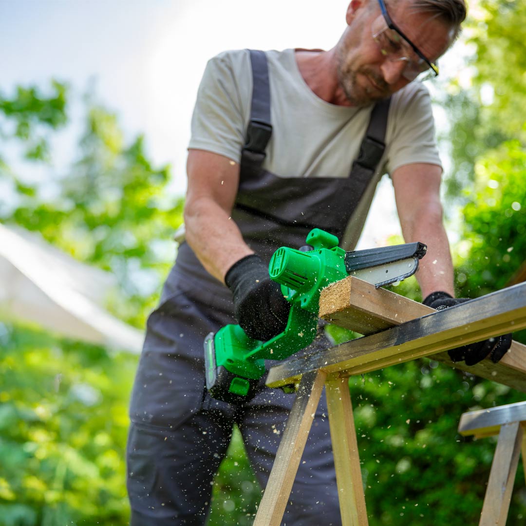 Mann sägt mit PocketSaw Pro ein Holzbrett im Garten