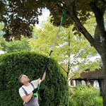 Mann sägt in seinem Garten mit der Hammersmith PocketSaw Pro kombiniert mit dem Teleskoptsiel einen Ast von einem Baum