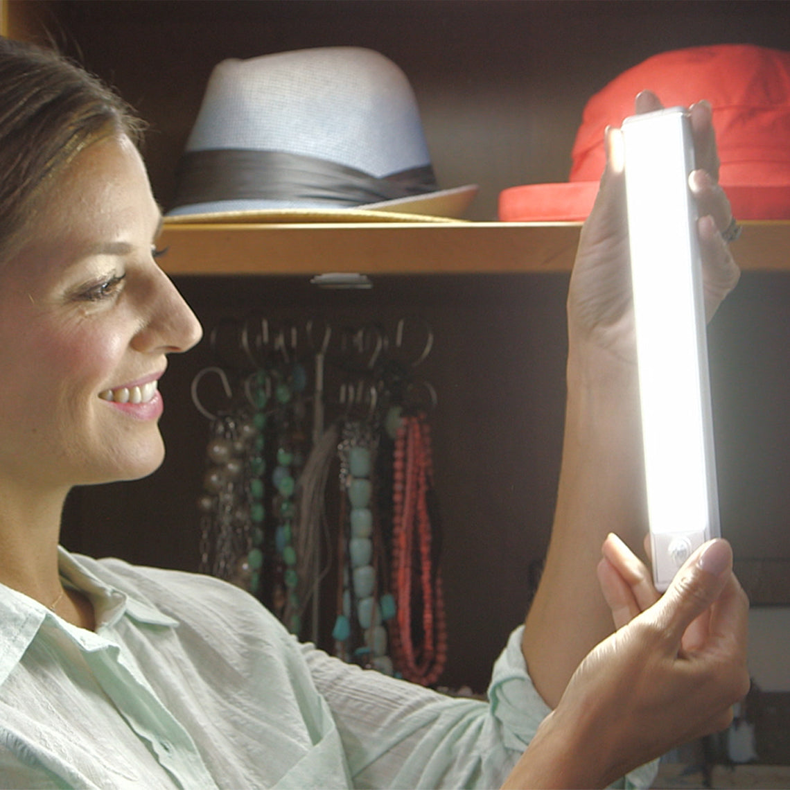 HandyLux Slim Bright – Frau schaltet tragbare LED-Leuchte ein, ideal für Kleiderschrank oder Flur.