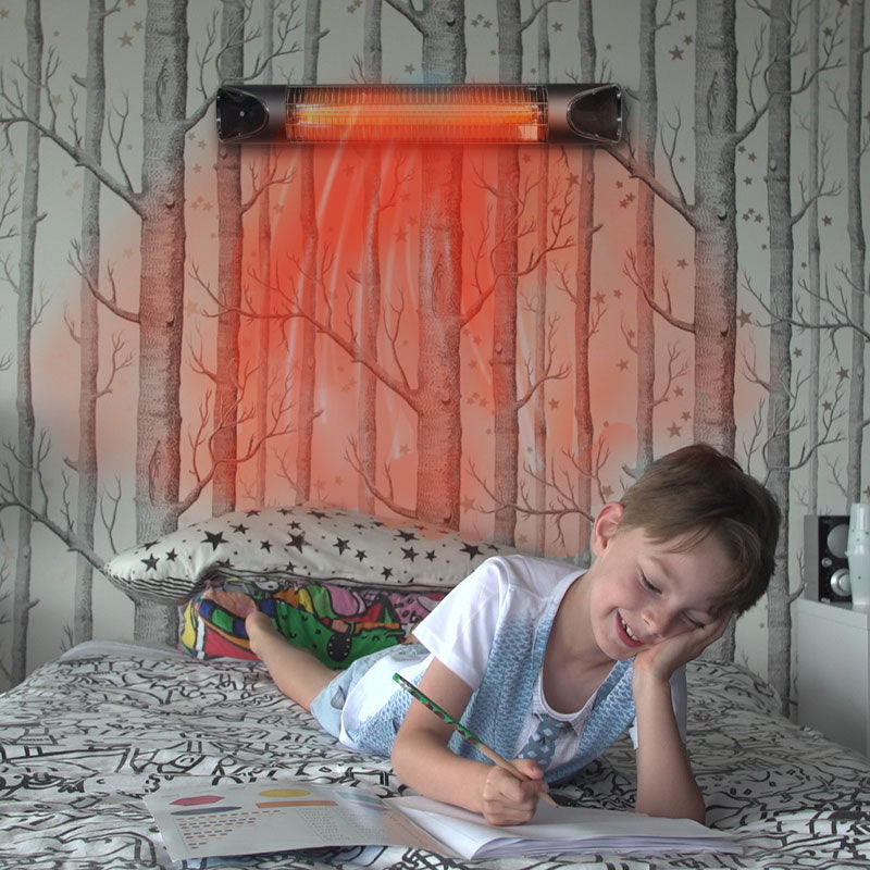Kind liegt im Bett und malt, beheizt durch den an der Wand montierten Livington Instant Heater.