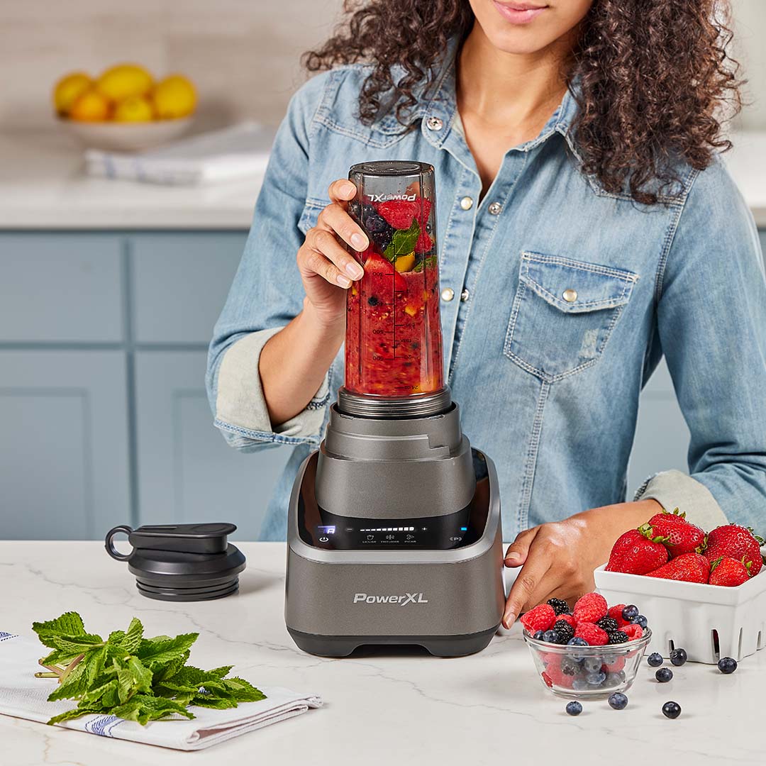 Frau mixt frische Zutaten im PowerXL SensiMax Blender auf der Küchenzeile