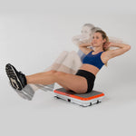 Frau trainiert ihre Bauchmuskeln im Sitzen auf der VibroShaper Deluxe Vibrationsplatte.