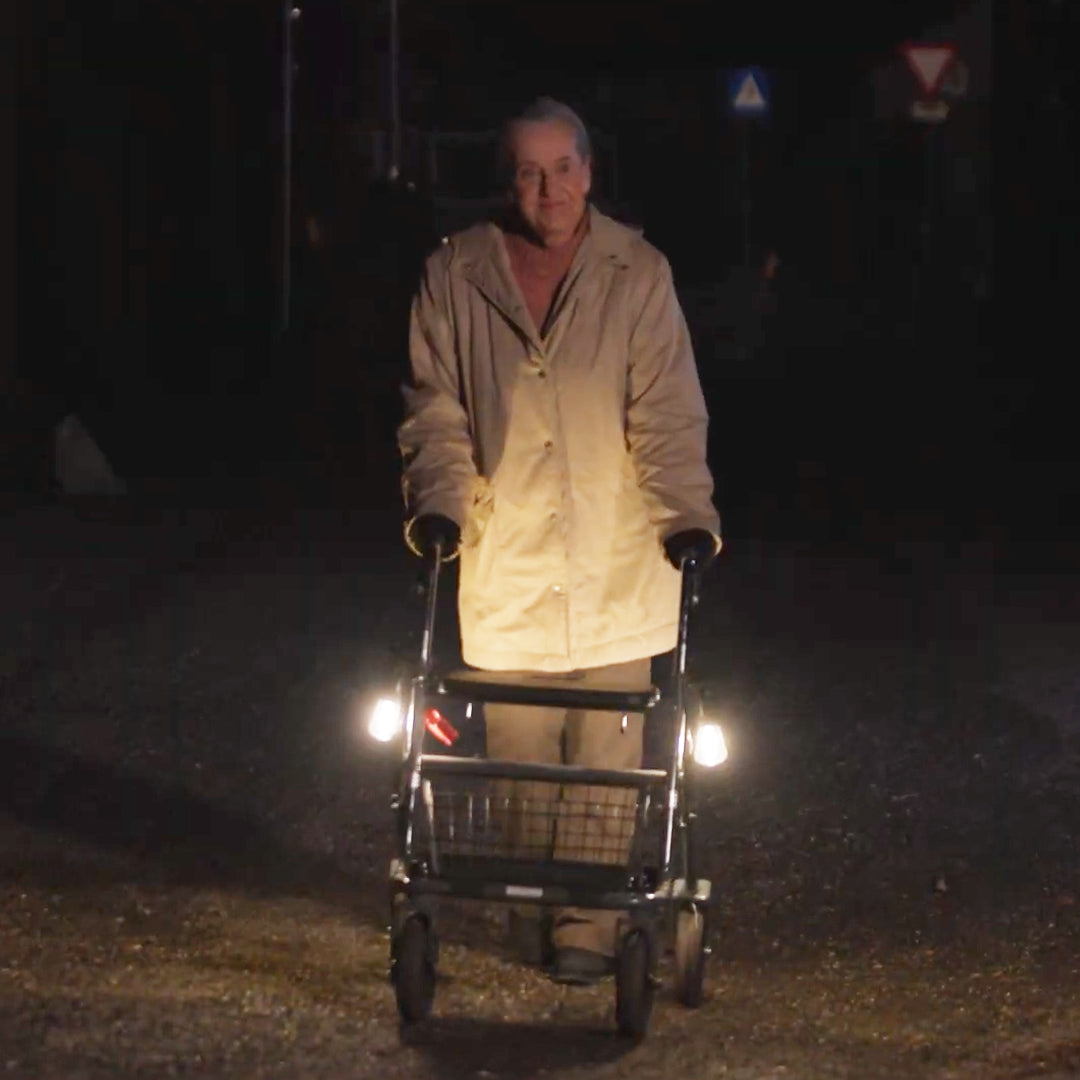Senior mit beleuchtetem Rollator bei Nacht unterwegs