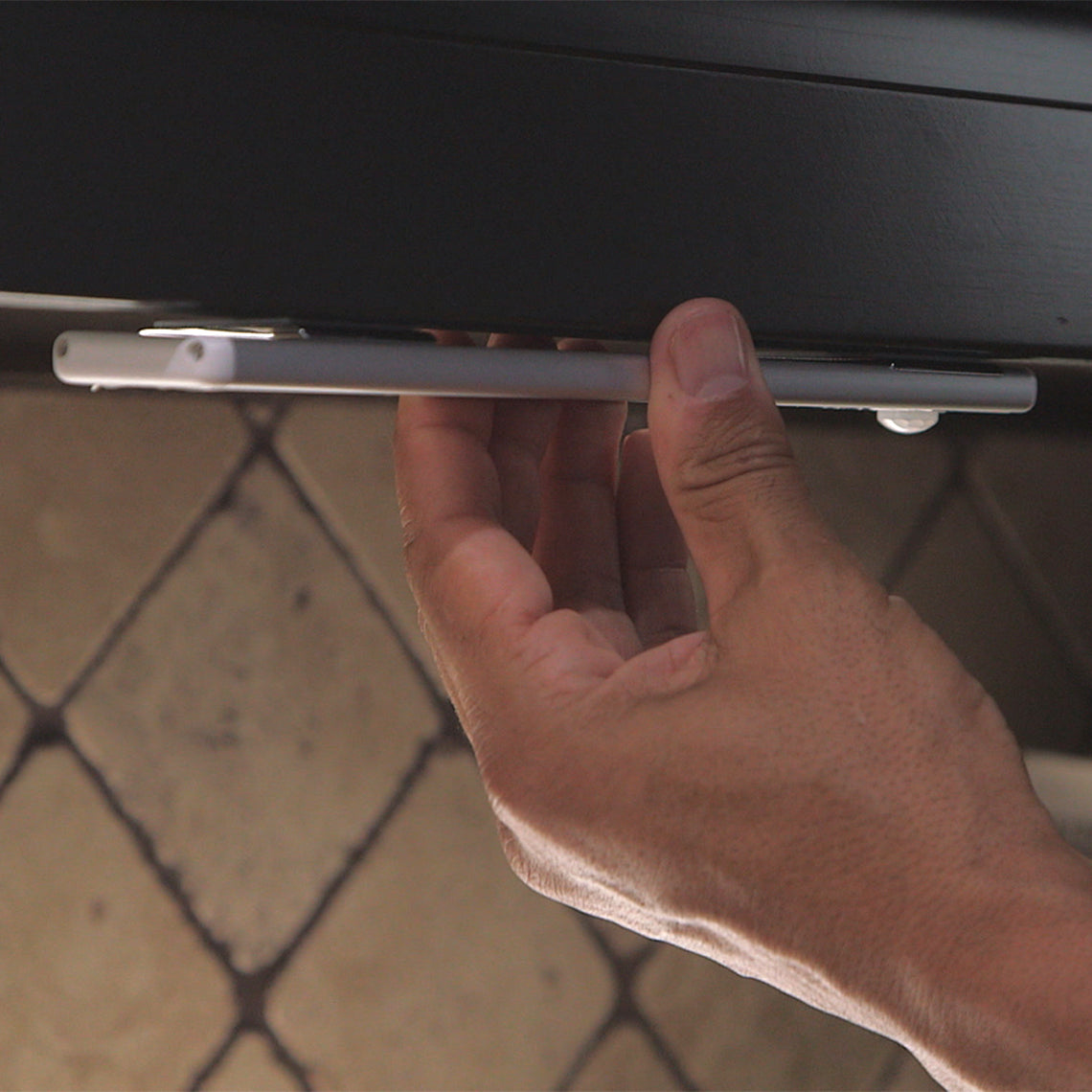 HandyLux Slim Bright – eine Hand befestigt die schlanke LED-Leuchte magnetisch unter einem Regal.