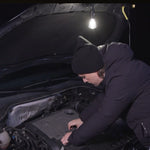 Person arbeitet bei Nacht am Motorraum mit aufgehängter LED-Leuchte