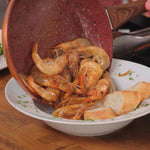 Garnelen werden aus der Copper and Stone Pan auf einen Teller mit Baguettescheiben serviert.