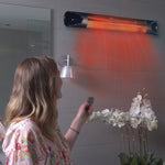 Frau schaltet im Badezimmer den Livington Instant Heater per Fernbedienung ein.