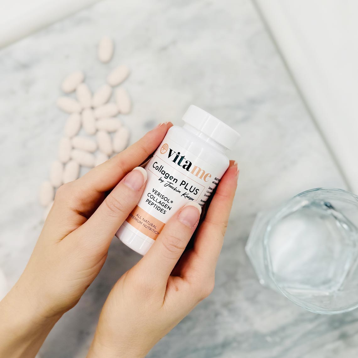 Hände halten eine Flasche „Collagen Plus“, daneben liegen Kapseln und ein Glas Wasser.