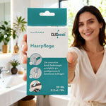 Frau hält eine Packung des ClicSwab Haarpflege-Stäbchens in die Kamera, im Hintergrund ein Badezimmer
