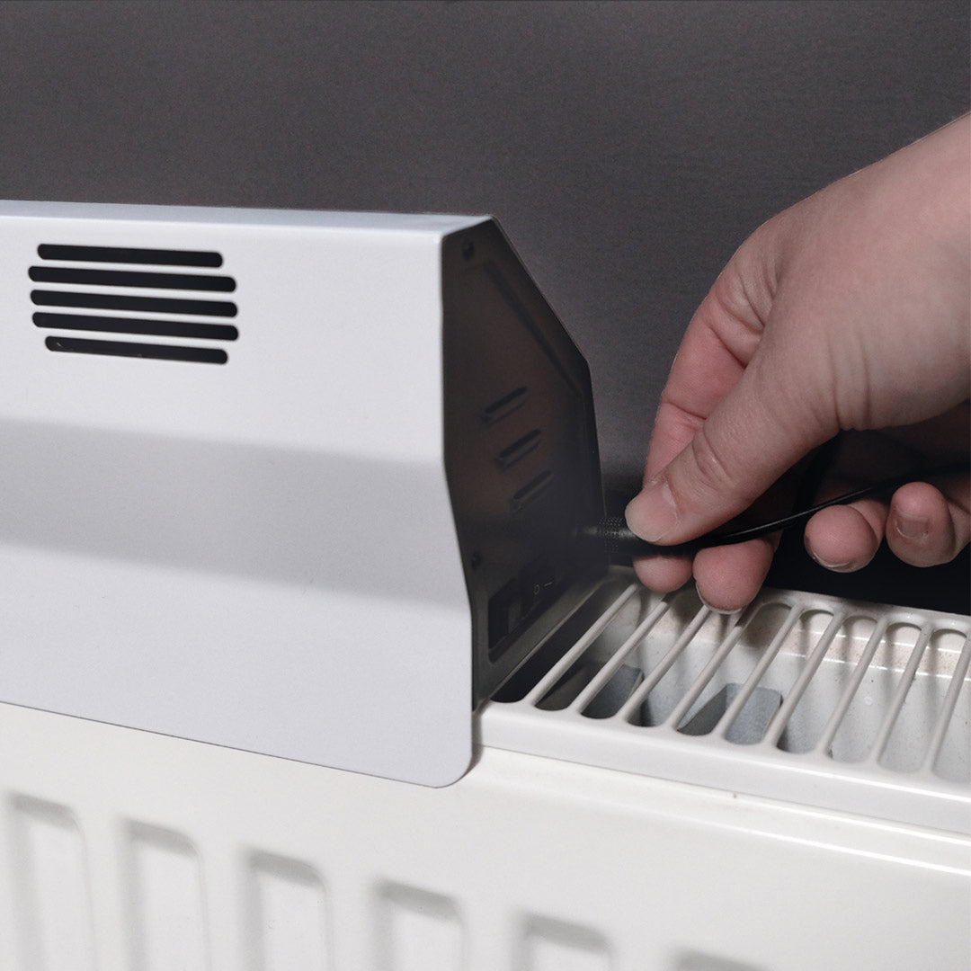 Netzstecker wird an den Livington SmartAir Heater angeschlossen, der auf einem Heizkörper montiert ist.