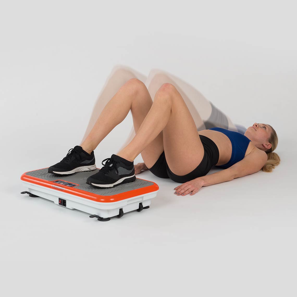 Frau macht Beckenlift-Übung mit den Füßen auf der VibroShaper Deluxe Vibrationsplatte.