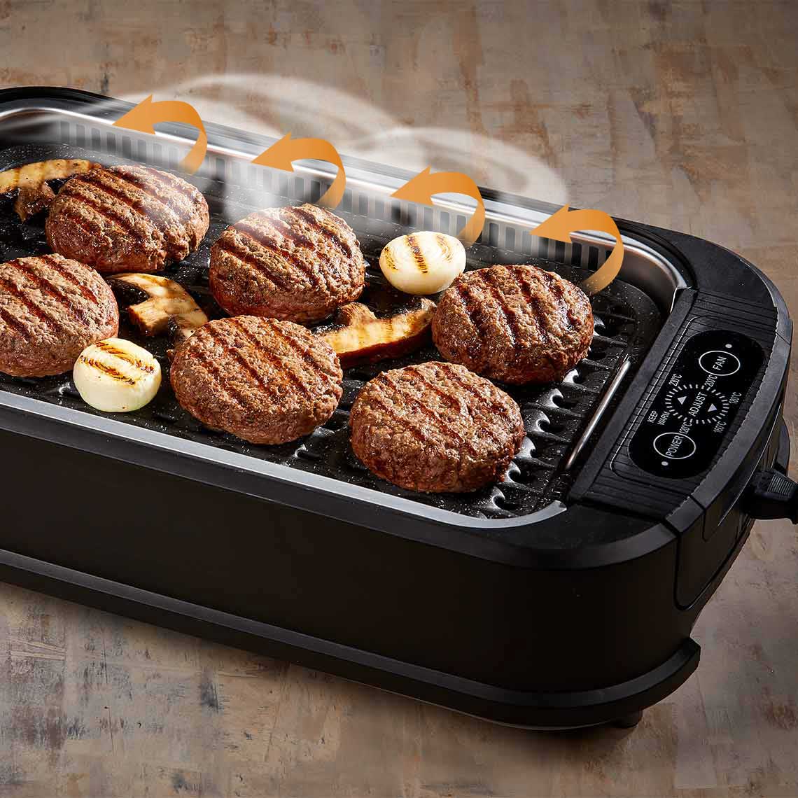 PowerXL Smokeless Grill – Burger und Gemüse auf Grillplatte, Pfeile zeigen aktive Rauchabsaugung.
