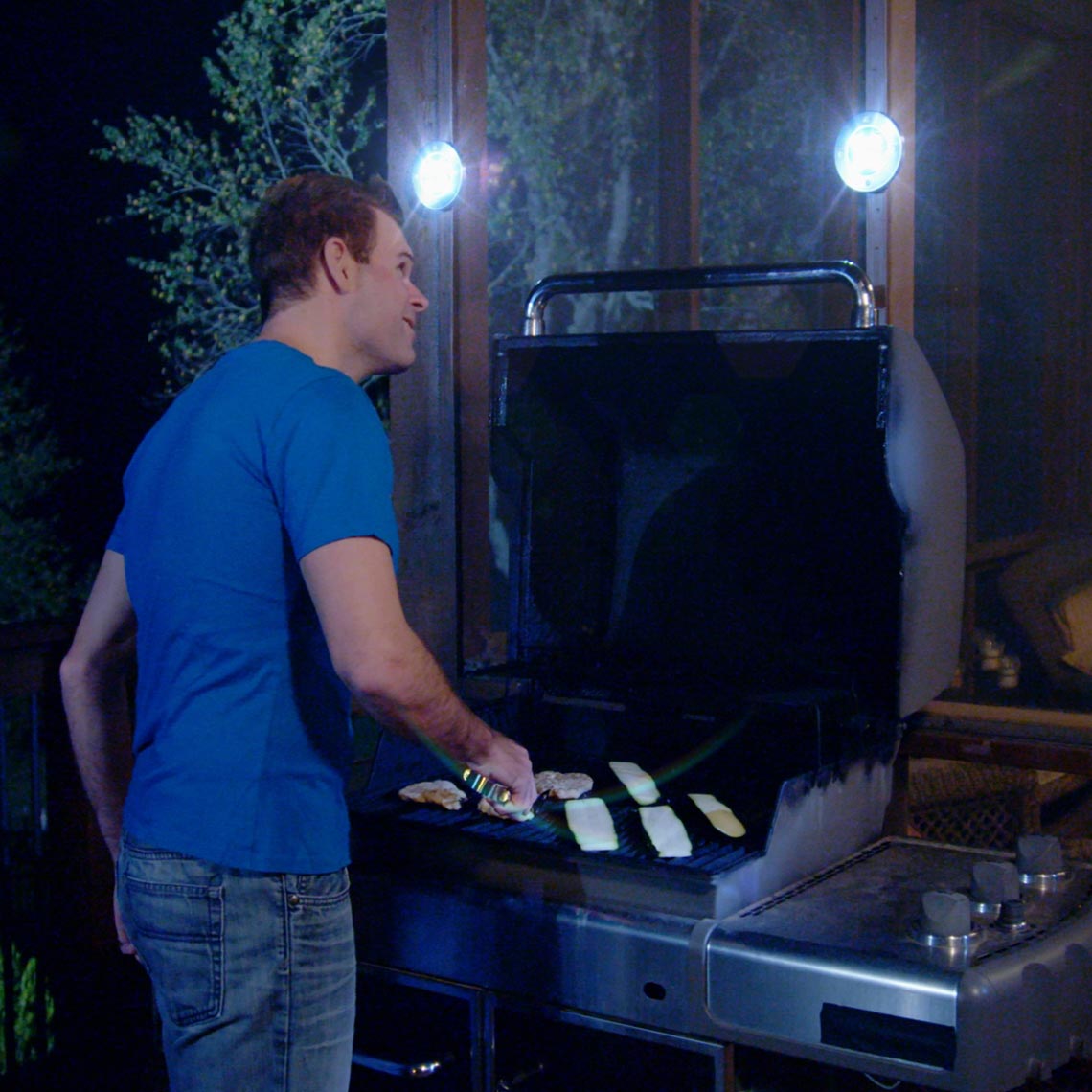 Mann grillt bei Nacht, beleuchtet von LED-Solarleuchten.