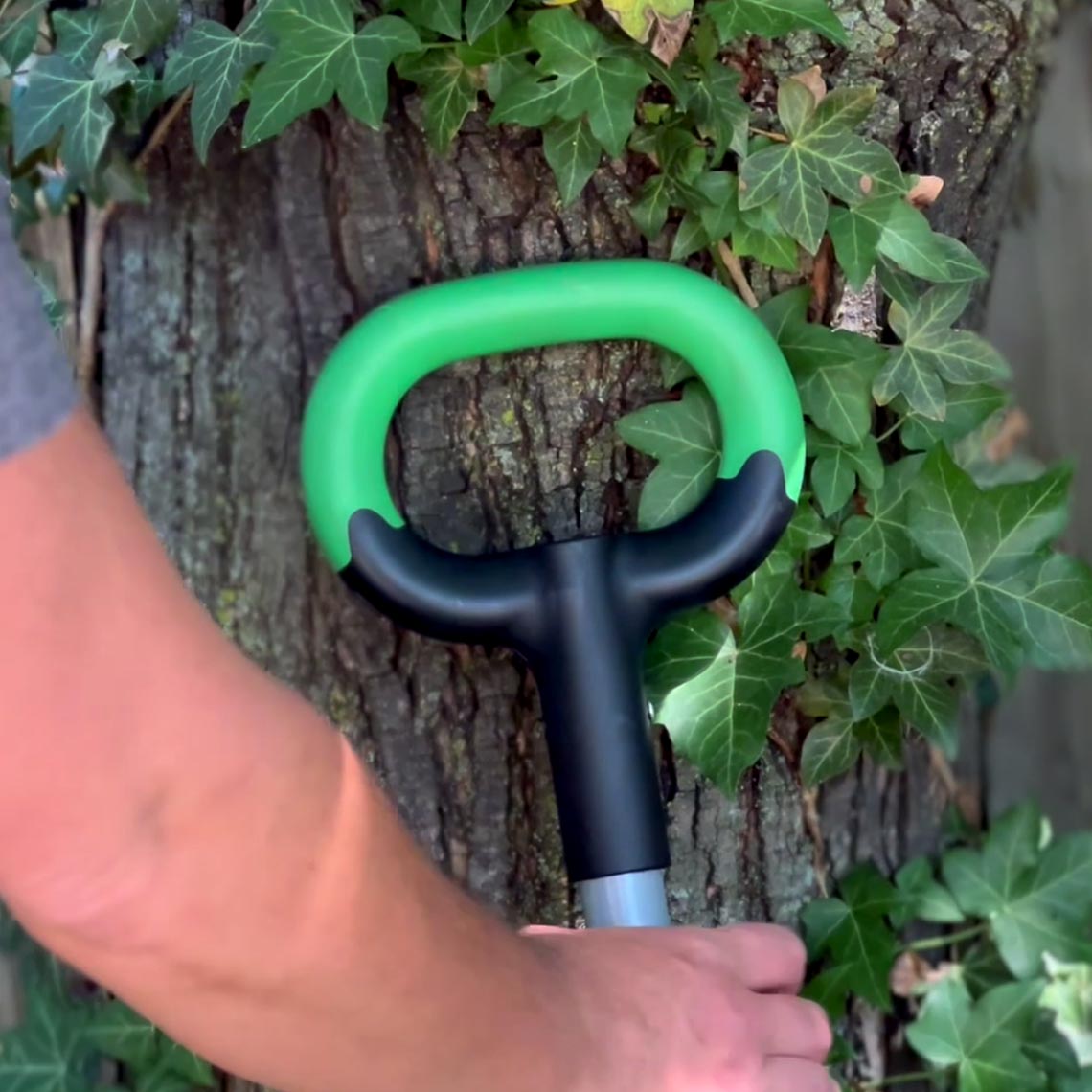 Der ergonomische Griff der Hammersmith Rayzor Shovel wird vor einem Baum mit Efeu gehalten.