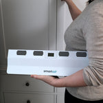 Eine Frau trägt den Livington SmartAir Heater kompakt in der Hand vor einem Schrank.