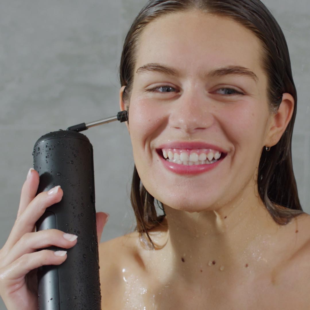 Frau reinigt ihr Ohr mit dem Wush sanft unter der Dusche.
