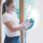 Eine Frau bedient den Livington SteamTouch Dampf-Handreiniger und reinigt ein Fenster mit heißem Dampf.