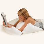 Frau liest auf dem Bauch, abgestützt vom Dreamolino Flip Pillow – bequem für Arme und Oberkörper.