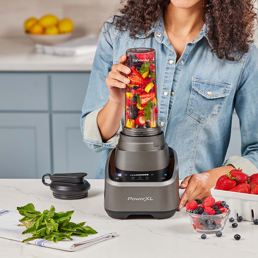 Frau bereitet einen Smoothie zu und füllt den PowerXL SensiMax Mixbehälter