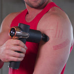 Mann massiert Schulter mit Massagepistole