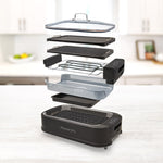 PowerXL Smokeless Grill – Explosionsdarstellung aller Teile: Glasdeckel, Grillplatten, Lüfter, Fettwanne und Gehäuse.