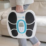 Person trägt das Fllow Fußmassagegerät am Griff in der Hand – tragbares, leichtes Design im modernen Look.
