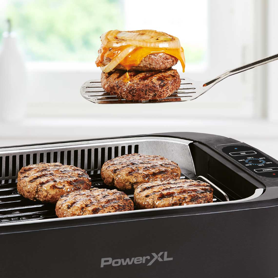 PowerXL Smokeless Grill – saftige Burger auf Grillplatte, einer mit Käse und Zwiebel wird serviert.