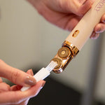 Nahaufnahme eines elektrischen Beauty-Geräts mit goldfarbenem Aufsatz, dessen Scherkopf mit einer kleinen Reinigungsbürste sorgfältig gereinigt wird.