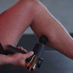 Massagepistole mit Schaumkopf-Aufsatz am Bein