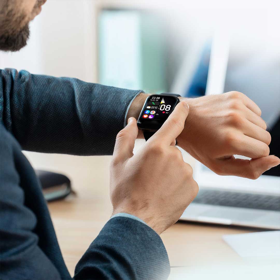 Ein Mann in Businesskleidung bedient den Kendox LifeTracker am Handgelenk im Büro.